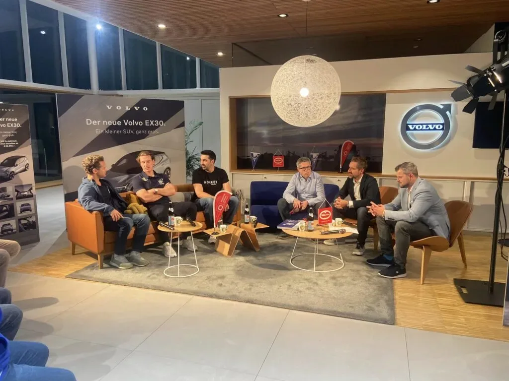 Diskussionsrunde mit sechs Personen in modern beleuchtetem Raum unter Volvo-Logo.